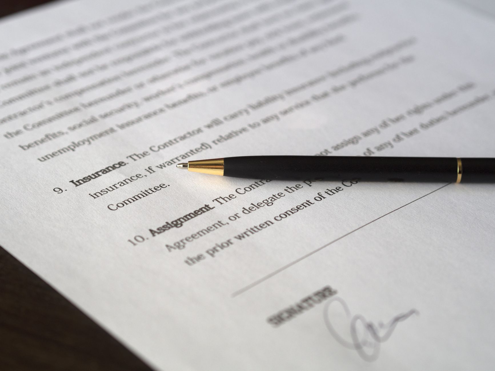 A printed contract with a pen resting on it