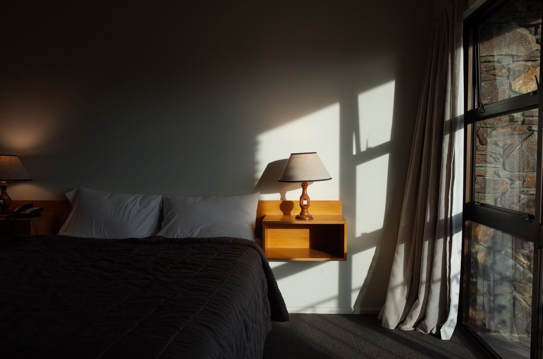 A quiet room with morning light and a made bed